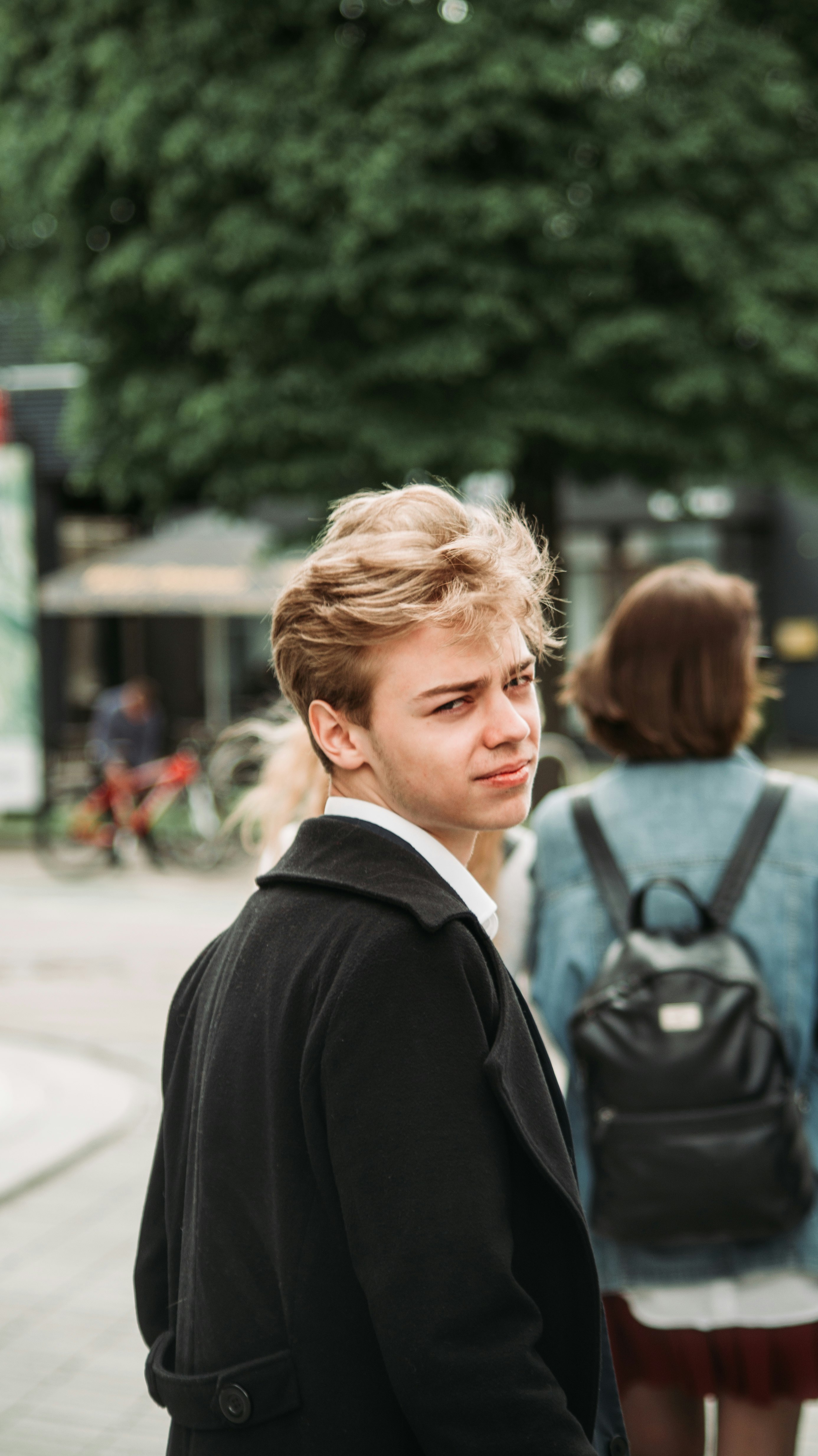 man in black suit jacket carrying black backpack